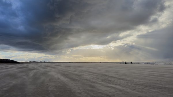 Dramatic clouds and golden hour light over Brancaster Beach in Norfolk.